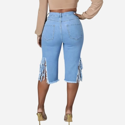 Women's high waisted ripped denim capri shorts raw hem chain distressed in blue, back view