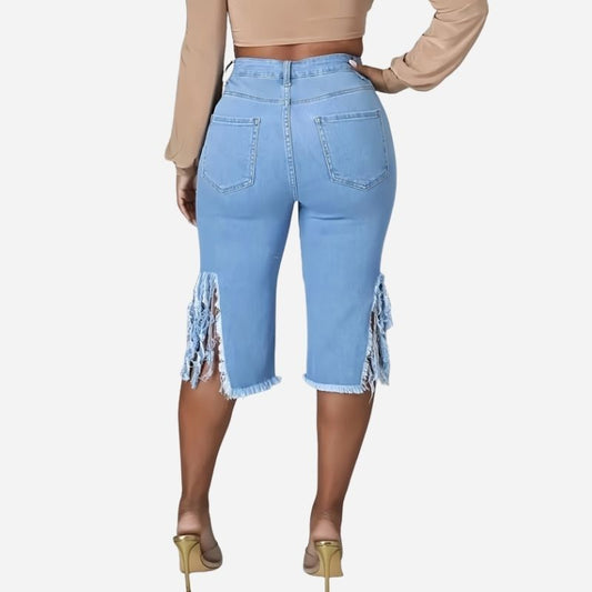 Women's high waisted ripped denim capri shorts raw hem chain distressed in blue, back view